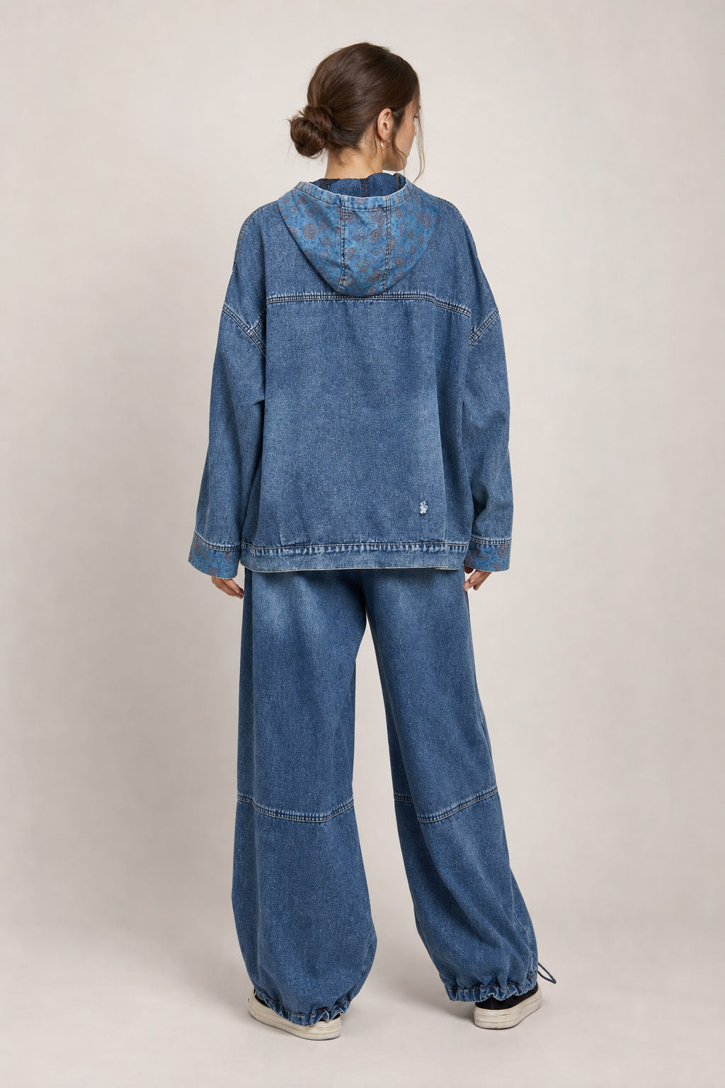 Vue de dos de l'ensemble denim, empiècements et surpiqûres apparentes sur la veste