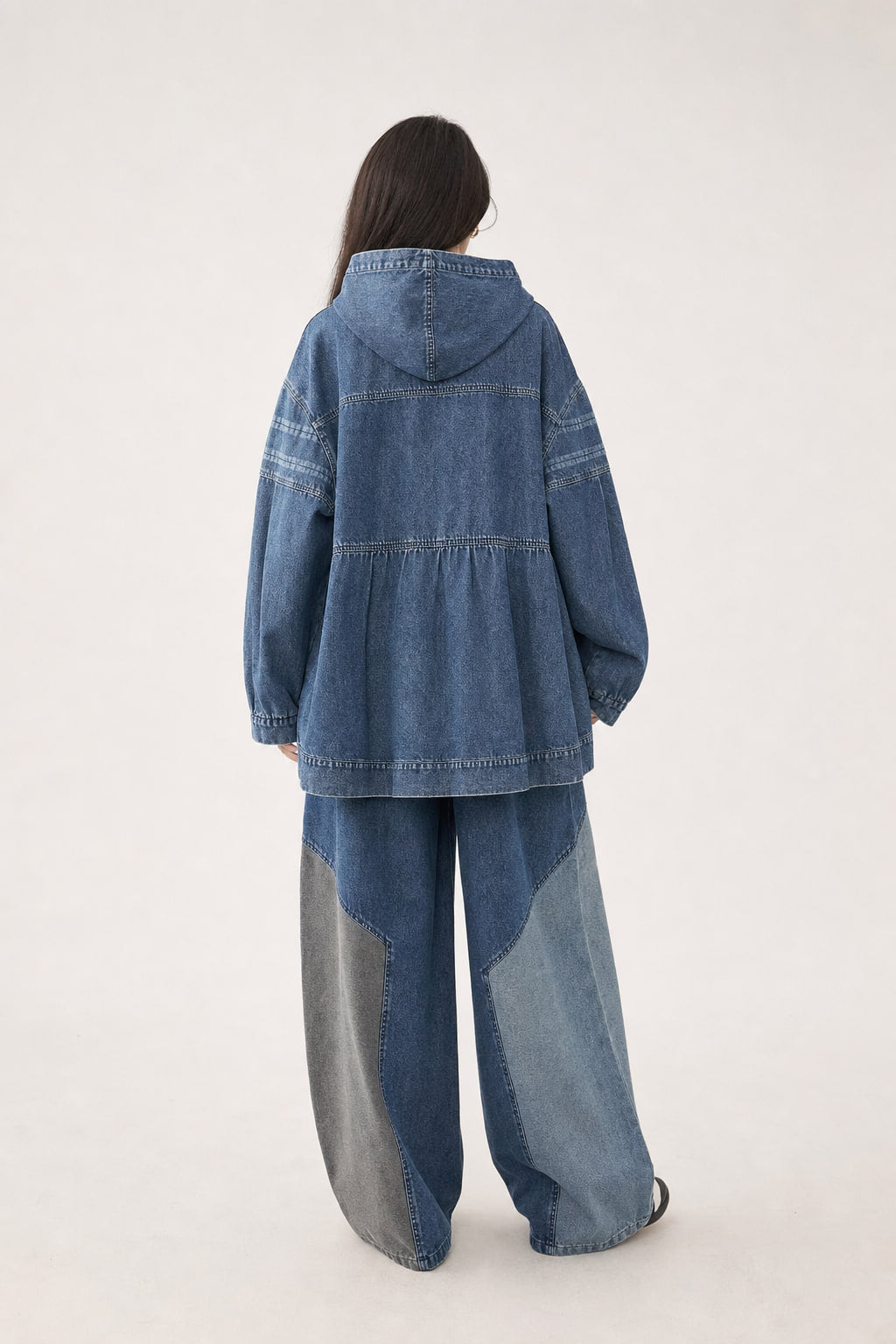 Dos de l'ensemble en denim noir, capuche rabattue et pantalon à jambe large