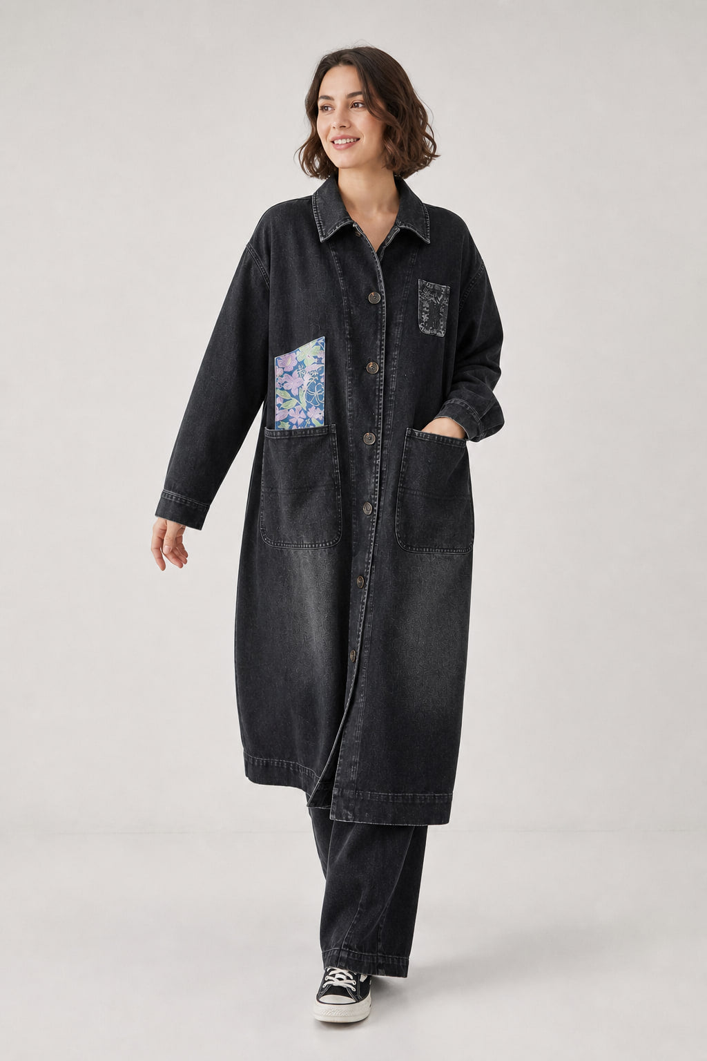 Manteau long denim noir en mouvement, volume oversize ouvert sur la silhouette