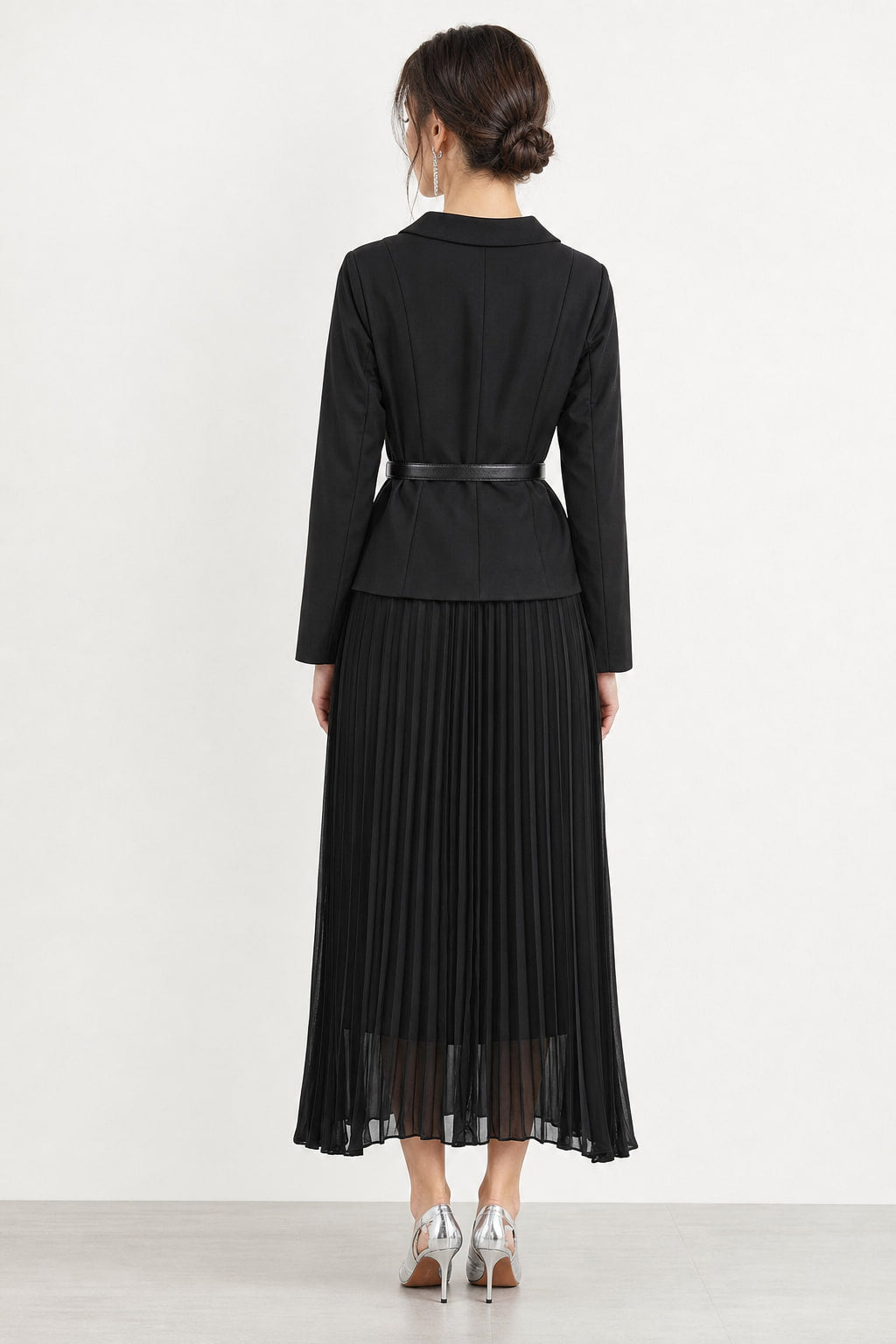 Dos de la robe noire, buste ajusté et jupe plissée tombant droit