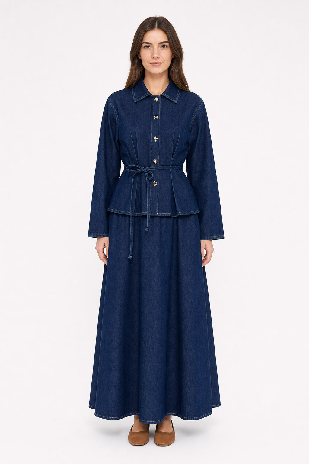 Ensemble en denim bleu profond vu de face : veste-chemise cintrée à boutons dorés et ceinture nouée, portée avec une jupe longue évasée tombant sur la cheville