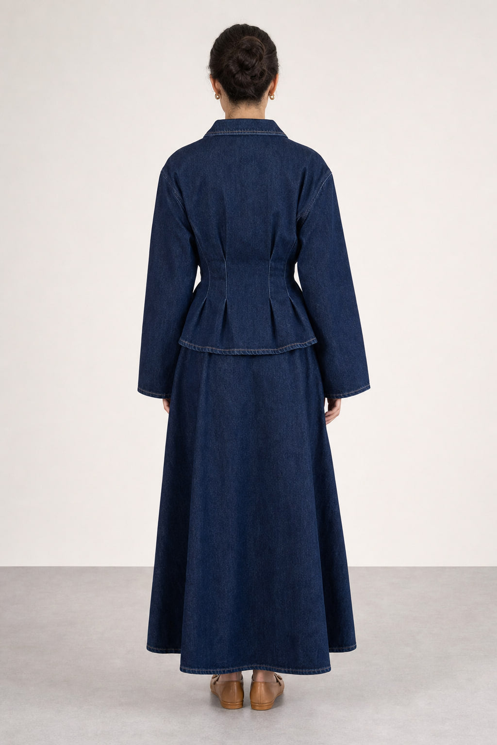 Ensemble en denim bleu profond vu de dos : basque courte de la veste-chemise et jupe longue à panneaux, ourlet ample jusqu'à la cheville