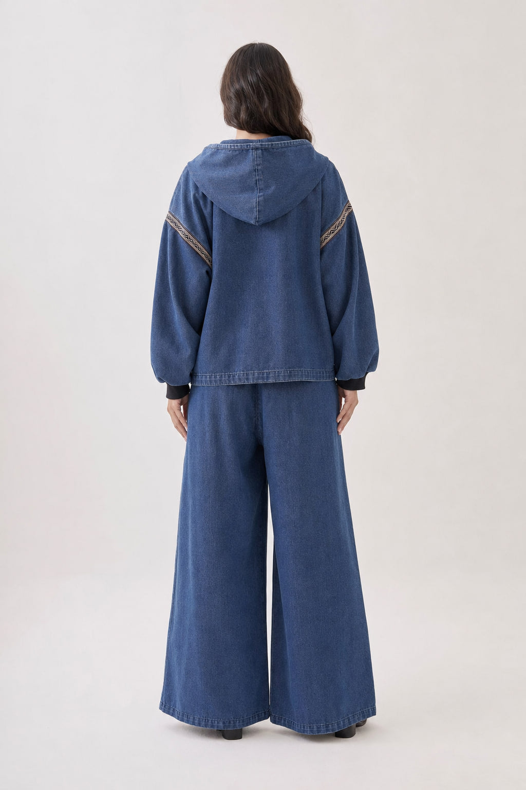 Vue de dos de l'ensemble en denim brodé, capuche et tombé du pantalon large