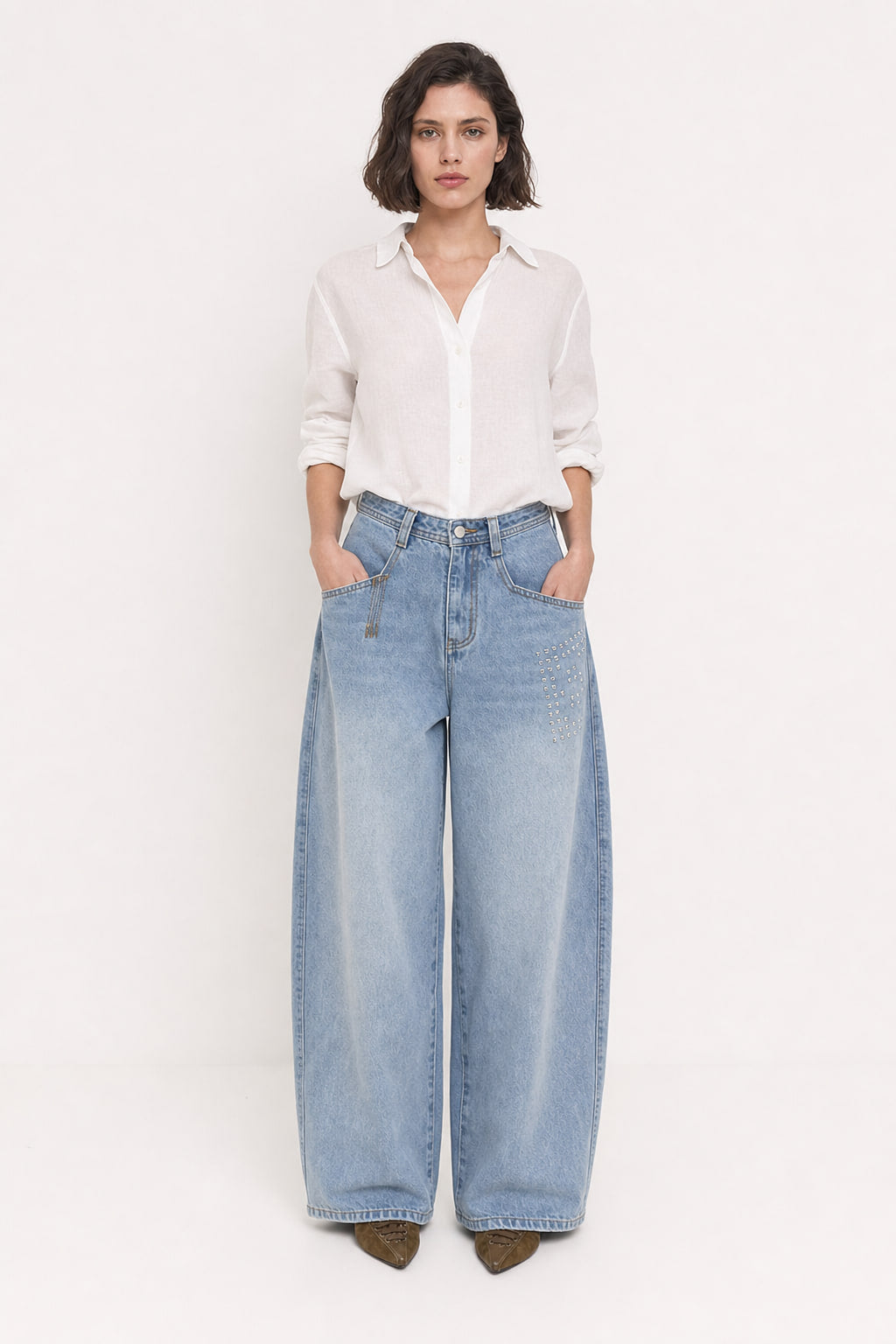 Jean baggy taille haute en denim clair vu de face, jambes arrondies et clous sur la cuisse droite