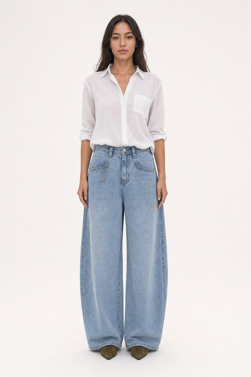 Jean large bleu clair délavé à jambe arrondie type cimeterre, taille mi-haute, avec clous métalliques sur la cuisse droite, vu de face