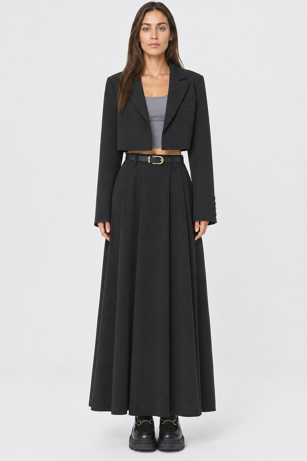 Jupe longue plissée taille haute portée de face, plis creux ouverts sur toute la largeur