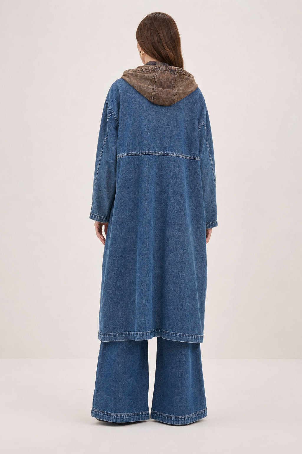 Dos du manteau long en denim bleu foncé, découpes de construction et capuche en velours côtelé