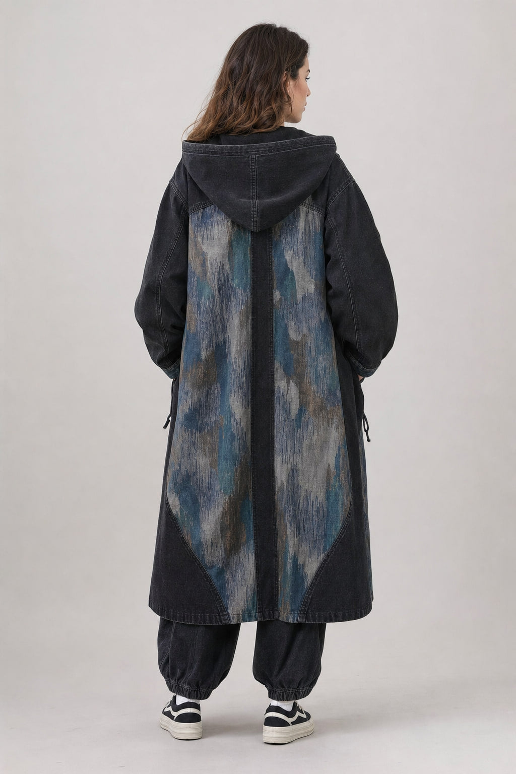 Vue de dos du manteau long oversize, découpes courbes des panneaux et capuche doublée