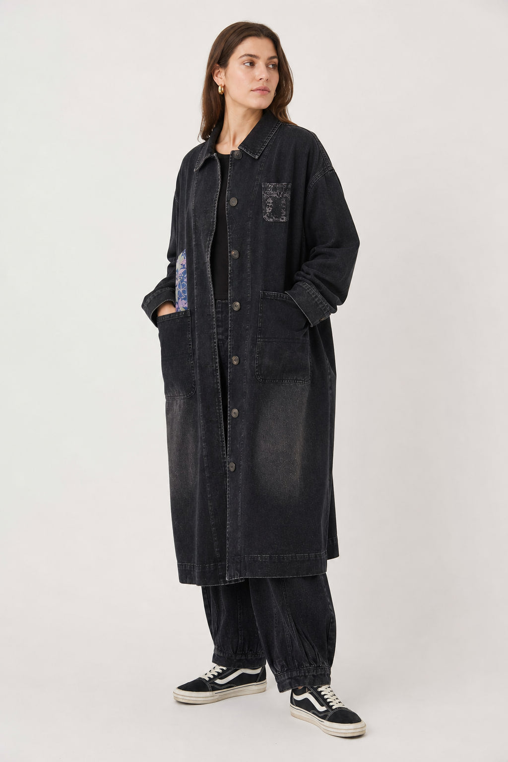 Vue de trois-quarts gauche du manteau long noir, grandes poches plaquées basses