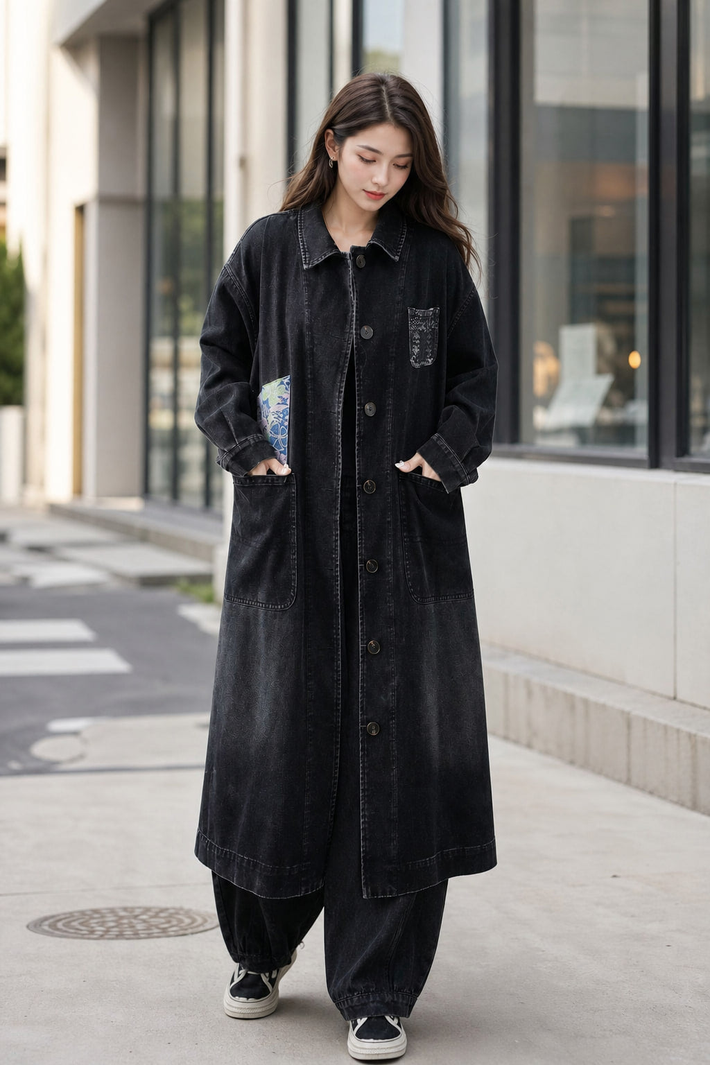 Manteau long en denim délavé noir porté en situation avec un jean droit et des sneakers