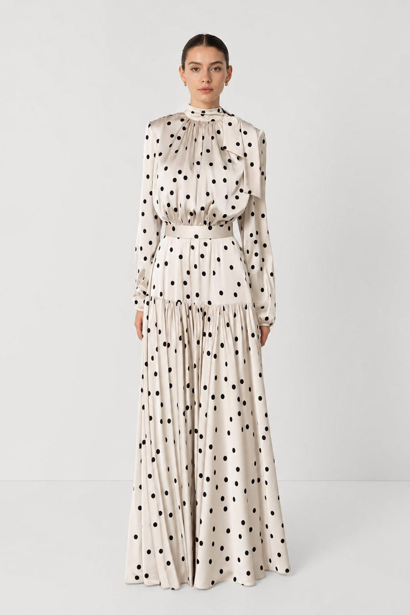 Robe longue satinée à pois noirs sur fond crème, vue de face, col montant et taille haute marquée
