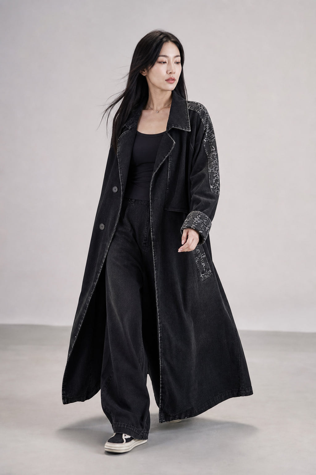Trench long en denim noir en mouvement, tombé fluide et évasé vers le bas