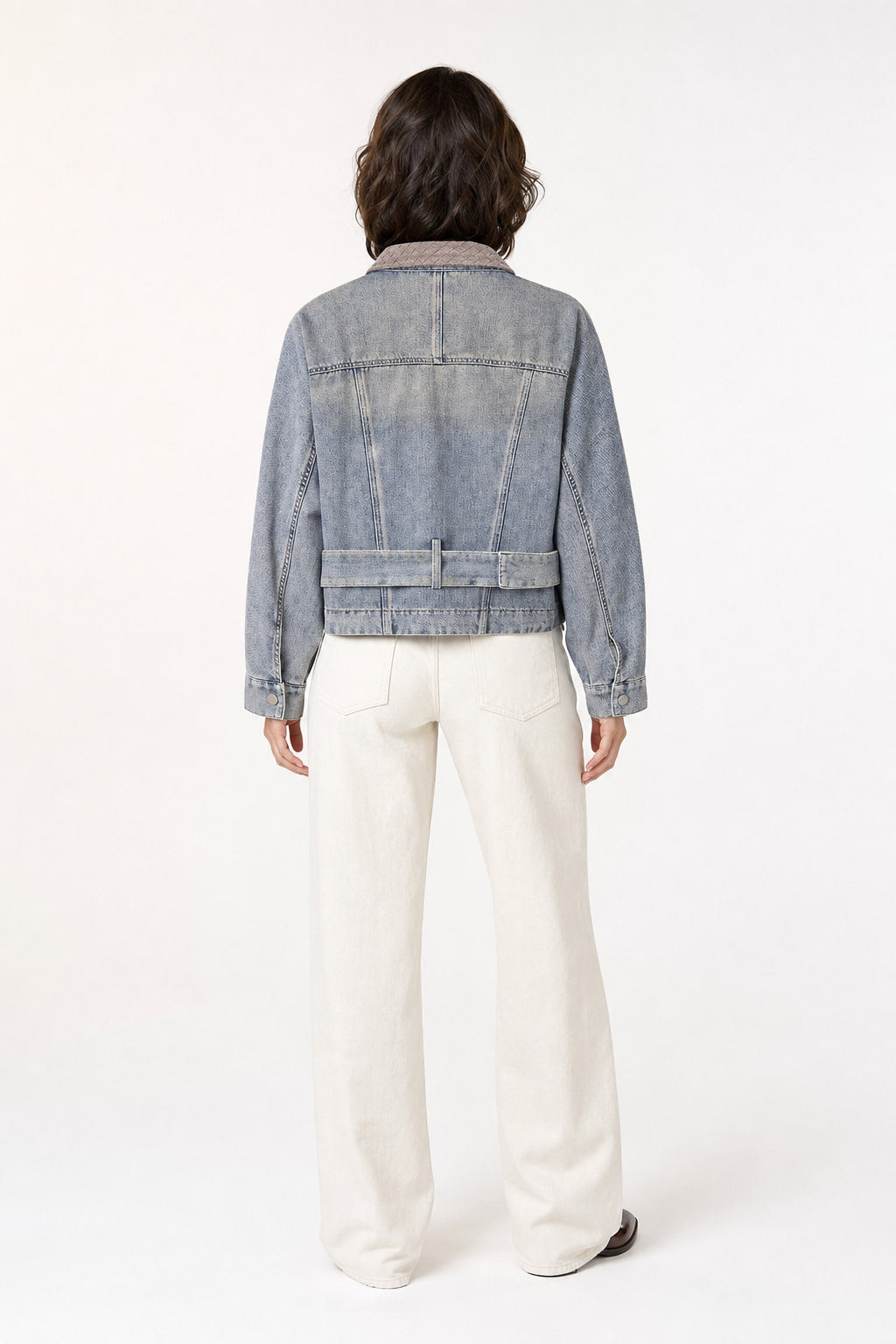 Dos de la veste en denim bleu, découpes et surpiqûres apparentes